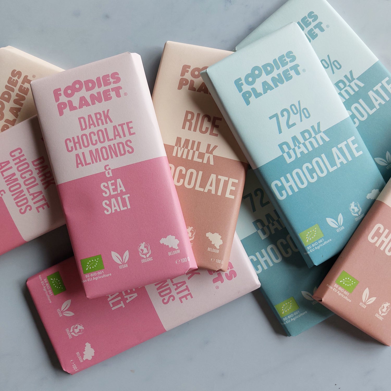 Vegan and organic chocolate bars from FOODIES-PLANET displayed on a marble table.