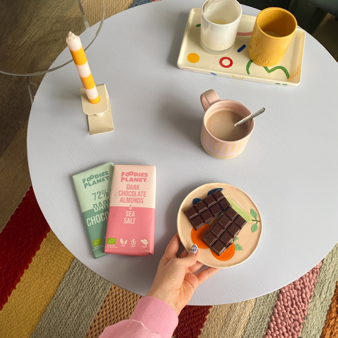 Vegan and organic chocolate from FOODIES-PLANET on a table with a cup of coffee.
